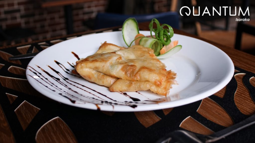 Crêpe salée dorée garnie de légumes finement sculptés et de traits de réduction de vinaigre balsamique au restaurant Quantum Isoraka.