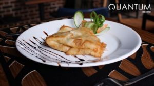 Crêpe salée dorée garnie de légumes finement sculptés et de traits de réduction de vinaigre balsamique au restaurant Quantum Isoraka.