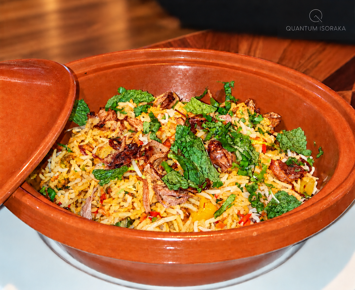 Biryani végétarien Quantum Isoraka, servi dans un plat en terre cuite sur un fond chaleureux en bois.