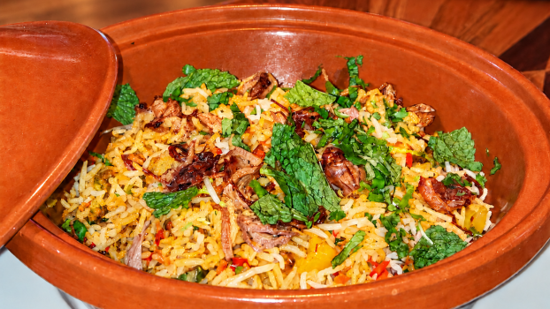 Biryani végétarien Quantum Isoraka, avec du riz parfumé servi dans un plat en terre cuite sur un fond chaleureux en bois.